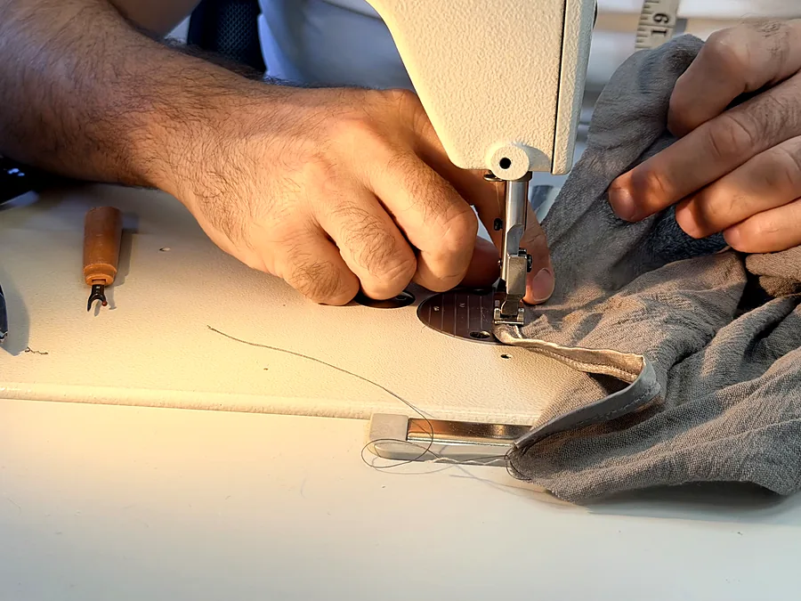 Our head of alterations guiding a garment under the needle on the industrial machine
